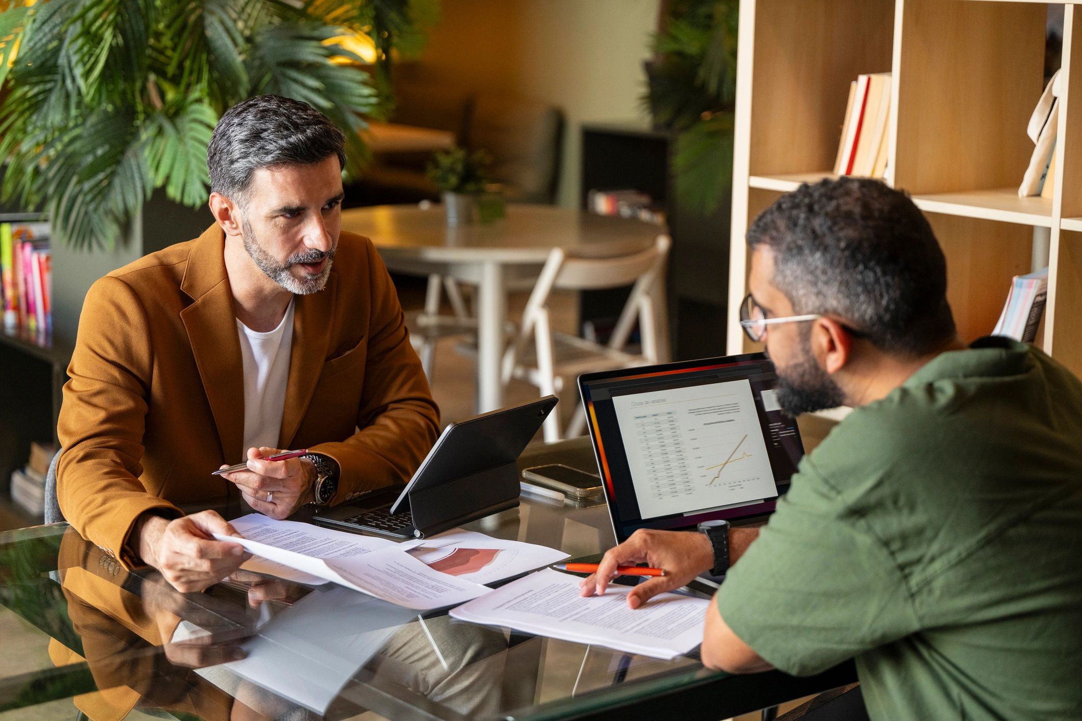 Two professionals reviewing paperwork and laptops in a private consultation